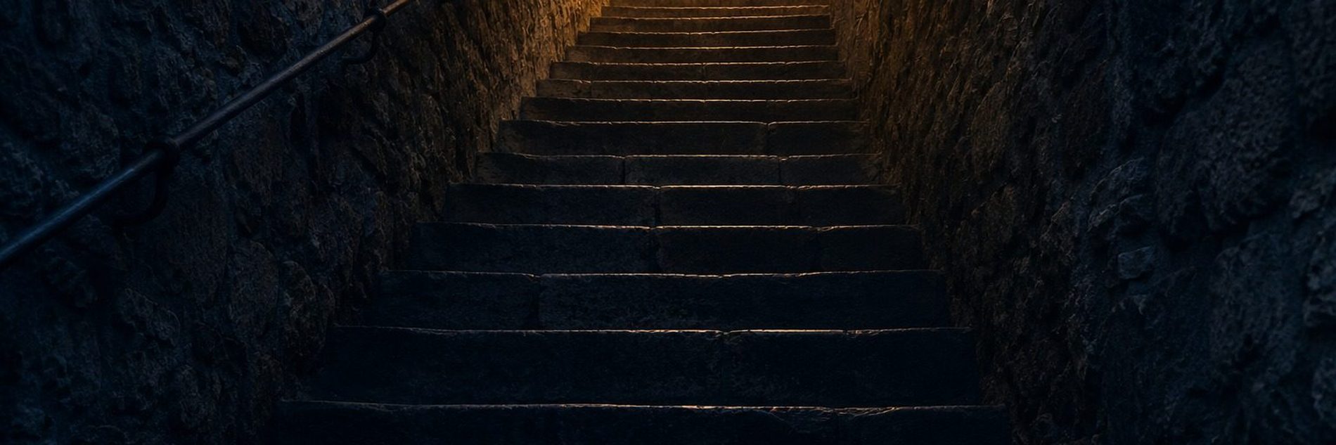 Worn stone steps climbing steeply towards light between two high walls