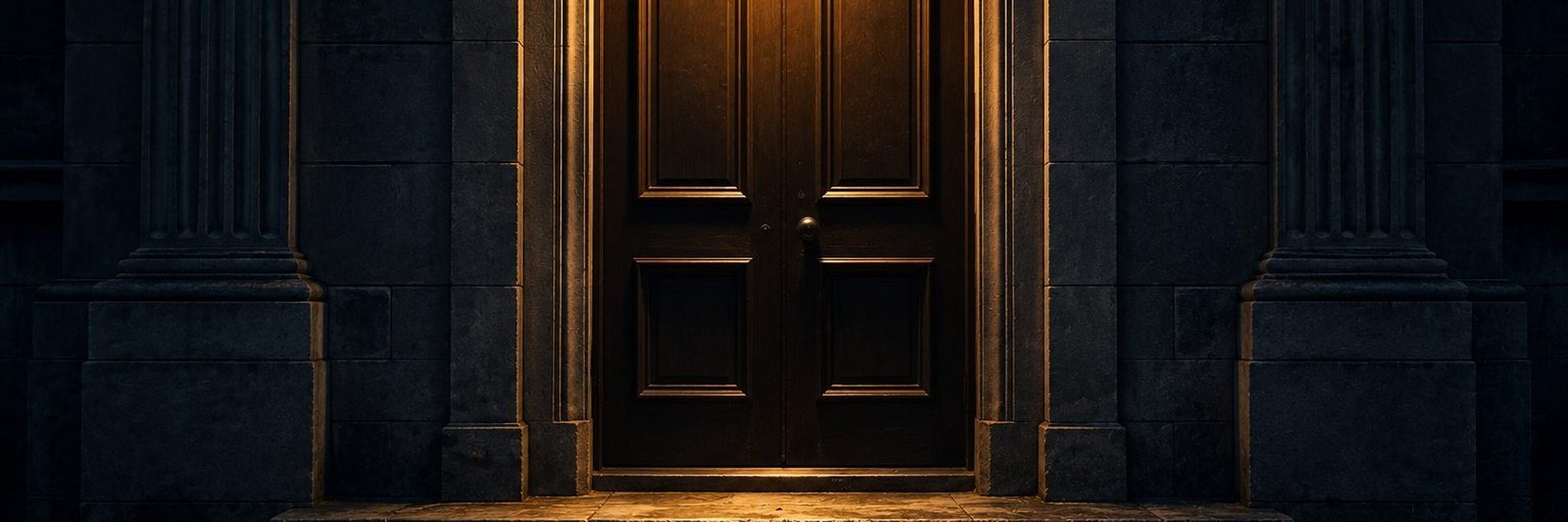 A heavy panelled door at the top of stone steps, lit from above at night