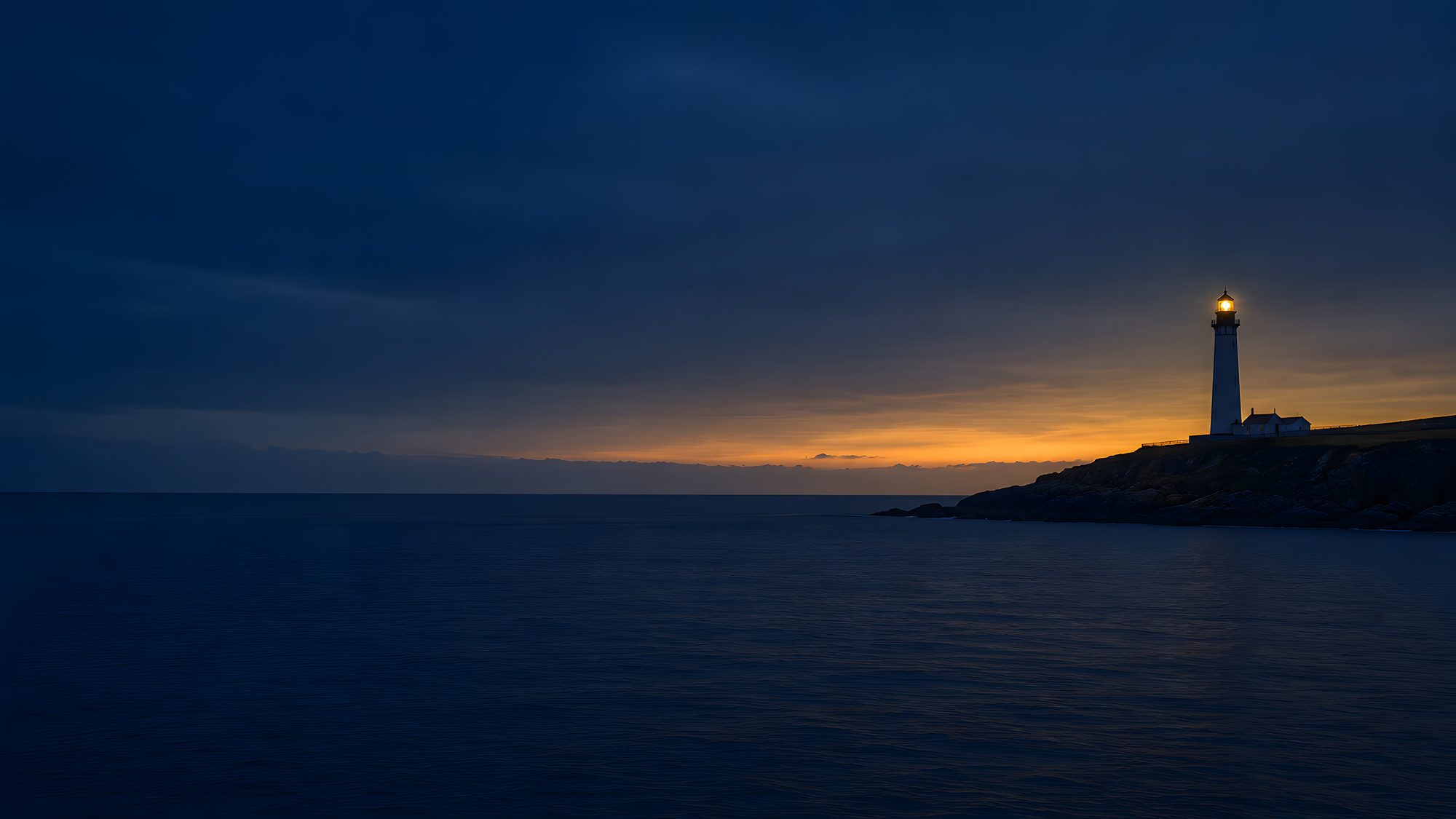 A lighthouse on a headland at first light, seen from open water